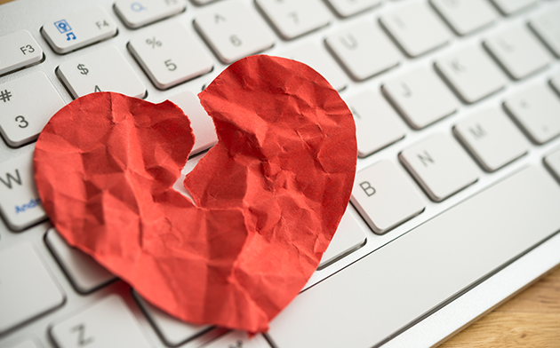 Paper cutout of broken heart on keyboard