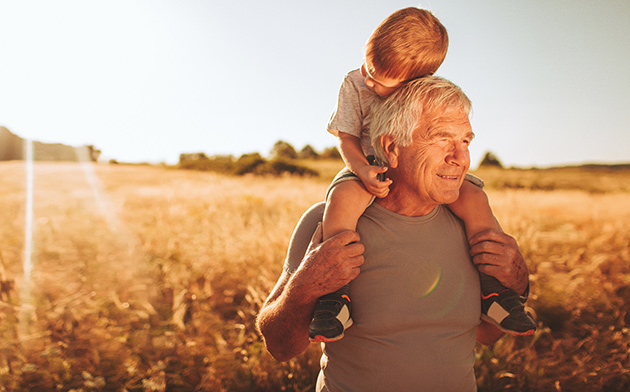 Older man giving young boy piggyback ride.