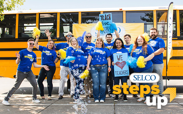 SELCO employees standing in front of a bus celebrating educators. 