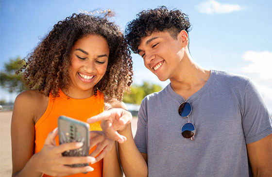 Girl and boy looking at the girl's phone while smiling. 