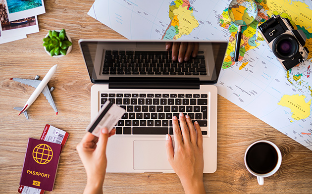 Two hands typing on a laptop and holding a credit card.