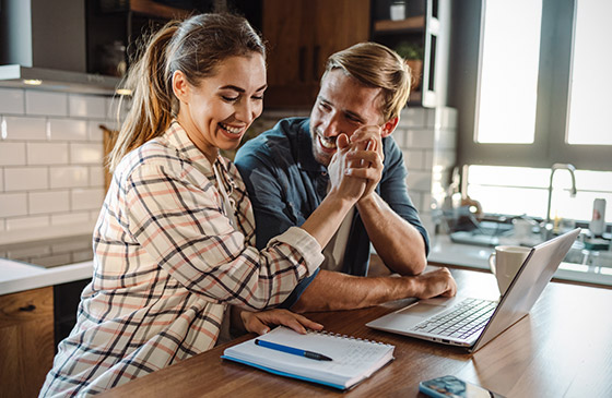 Man and woman sitting down at a computer high fiving. 