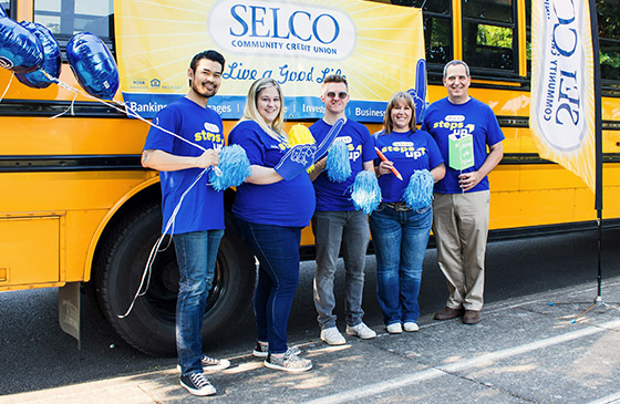 SELCO employees standing in front of a school bus celebrating educators.