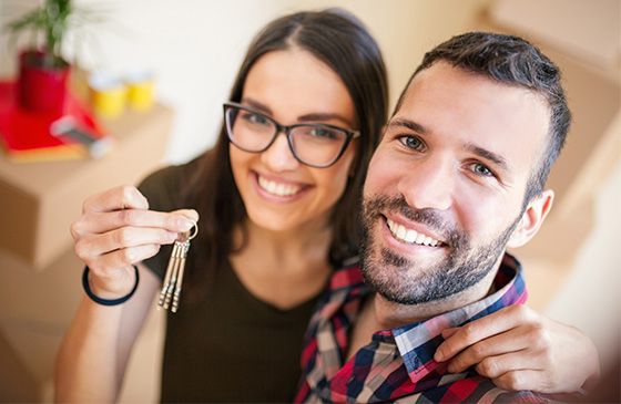 Man and woman holding keys to their first home. 