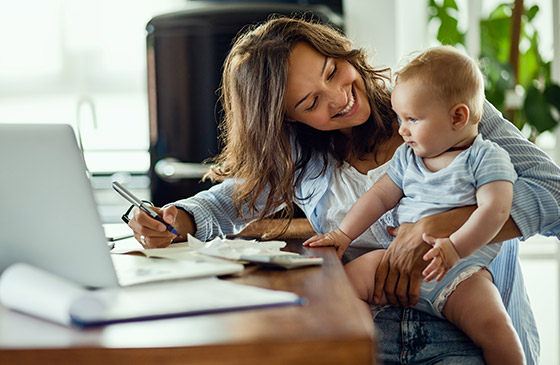 Woman sitting with her baby in front of a computer.